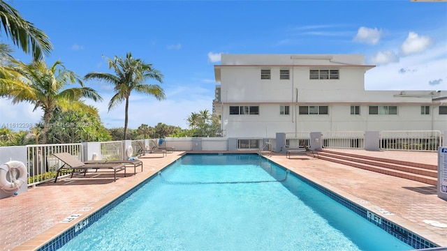 community pool with fence and a patio area