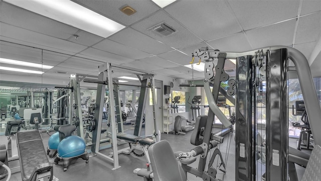 exercise room featuring a wealth of natural light, a drop ceiling, and visible vents