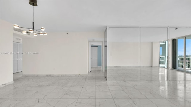 unfurnished room featuring marble finish floor, an inviting chandelier, floor to ceiling windows, and baseboards