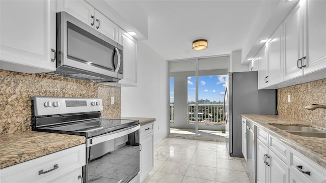 kitchen featuring a sink, tasteful backsplash, marble finish floor, white cabinets, and appliances with stainless steel finishes