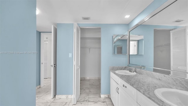 full bath with visible vents, marble finish floor, double vanity, and a sink