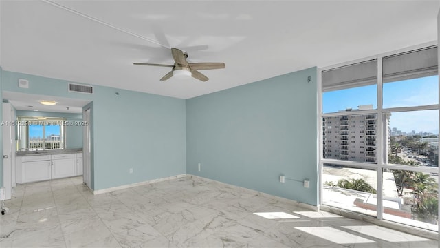 unfurnished bedroom featuring visible vents, baseboards, a city view, a ceiling fan, and ensuite bath