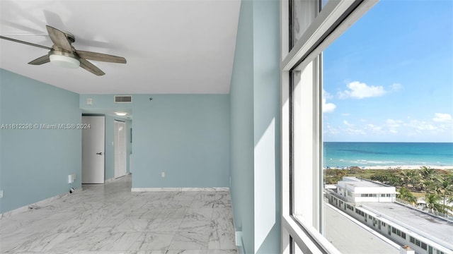 interior space with a beach view, ceiling fan, and a water view