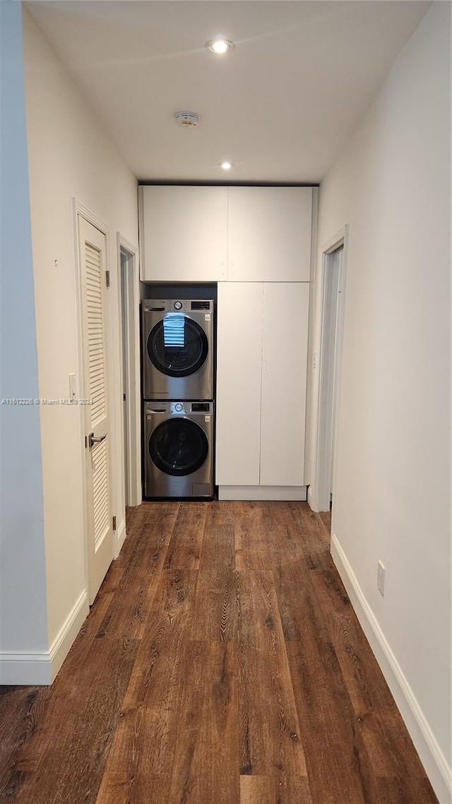 corridor featuring stacked washer and dryer and dark hardwood / wood-style flooring