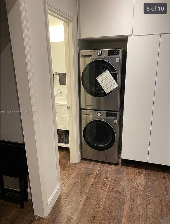 clothes washing area featuring stacked washer and clothes dryer and wood-type flooring