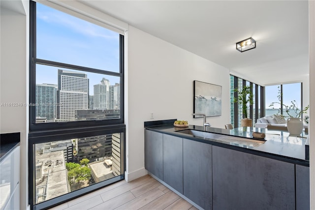 1010 Brickell Ave Unit 2201, Miami, FL 33131 - kitchen featuring a sink, light wood-style flooring, dark countertops, open floor plan, and baseboards