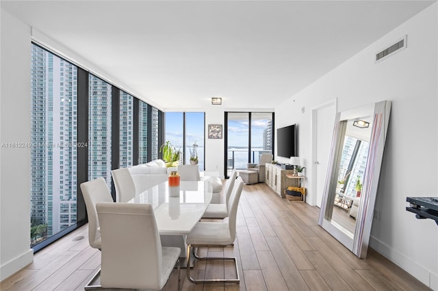 dining area with floor to ceiling windows and light hardwood / wood-style floors