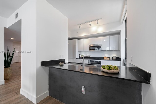 1010 Brickell Ave Unit 2201, Miami, FL 33131 - kitchen with stainless steel microwave, dark countertops, wood finished floors, white cabinetry, and baseboards