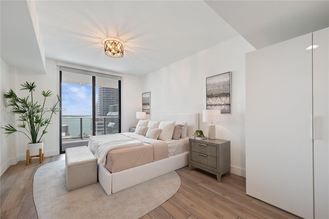 1010 Brickell Ave Unit 2201, Miami, FL 33131 - bedroom featuring light wood finished floors, a wall of windows, access to exterior, and baseboards