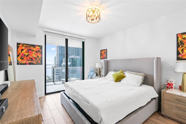 bedroom with light wood-type flooring, access to exterior, and expansive windows