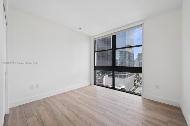 1010 Brickell Ave Unit 2201, Miami, FL 33131 - spare room with floor to ceiling windows, healthy amount of natural light, wood finished floors, baseboards, and a view of city