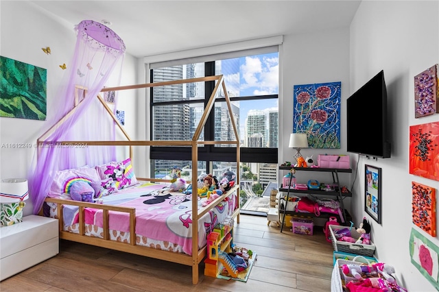 bedroom featuring hardwood / wood-style flooring, a wall of windows, and multiple windows