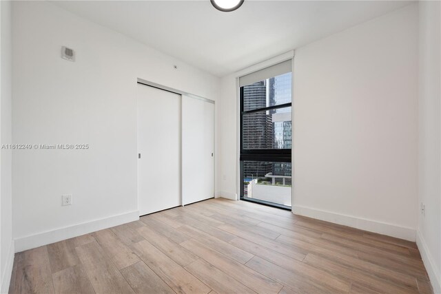 1010 Brickell Ave Unit 2201, Miami, FL 33131 - unfurnished bedroom featuring floor to ceiling windows, wood finished floors, a closet, and baseboards