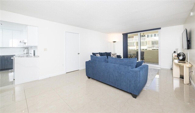 living room with floor to ceiling windows, sink, a textured ceiling, and light tile floors