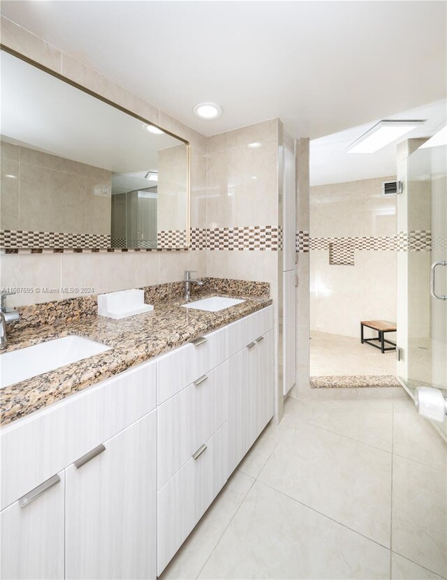 bathroom featuring tile flooring, double sink vanity, and tile walls