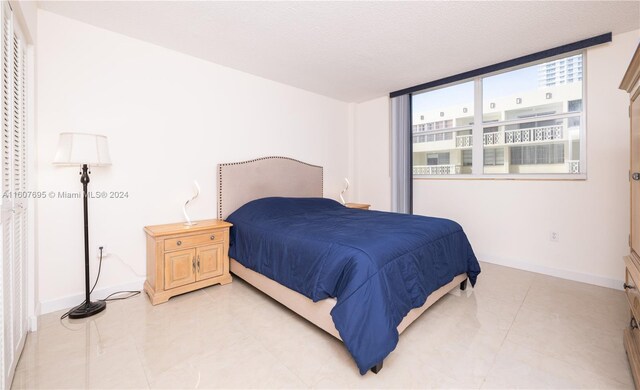 bedroom featuring a wall of windows and light tile flooring