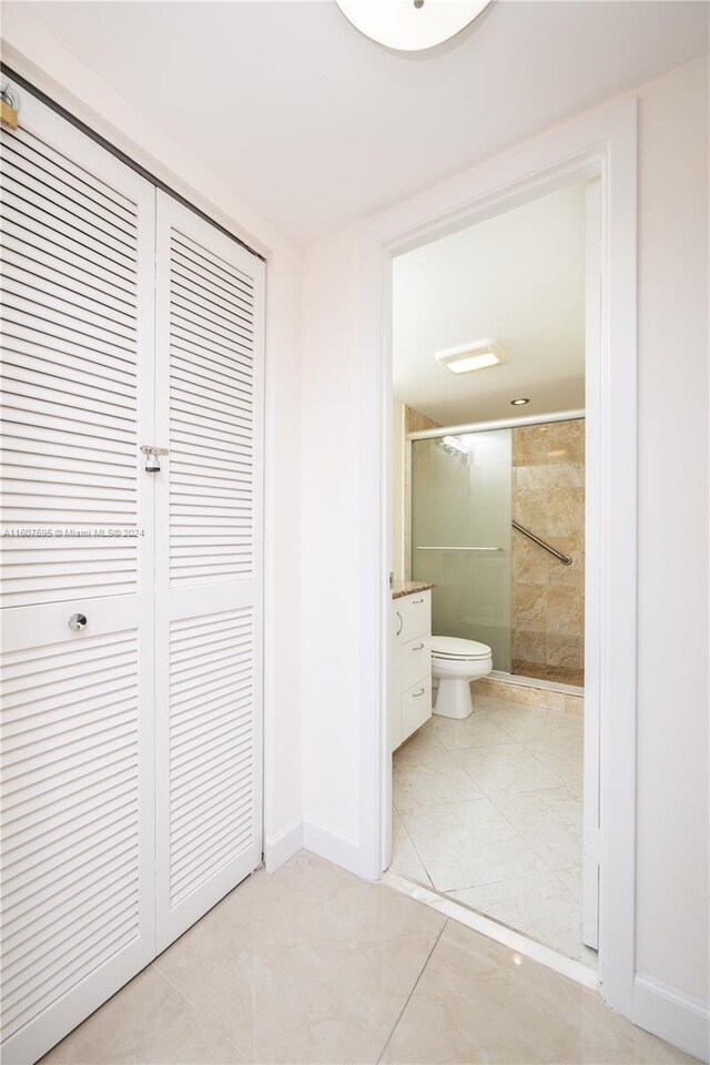 interior space with ensuite bathroom, a closet, and light tile floors