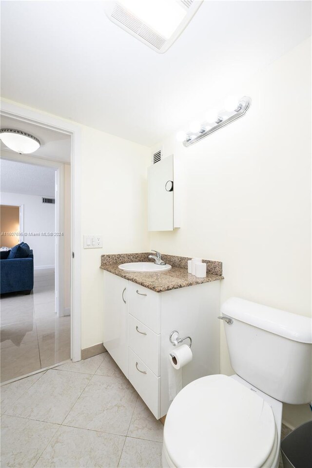 bathroom with tile flooring, toilet, and vanity