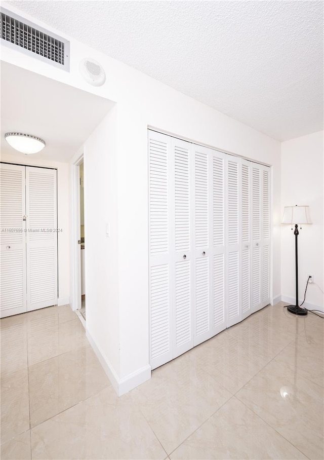 hallway featuring a textured ceiling and light tile floors