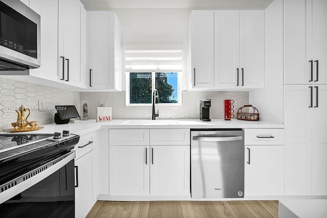 kitchen with decorative backsplash, appliances with stainless steel finishes, white cabinetry, and sink