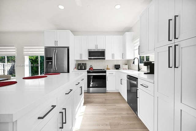 kitchen with appliances with stainless steel finishes, white cabinetry, a wealth of natural light, and sink