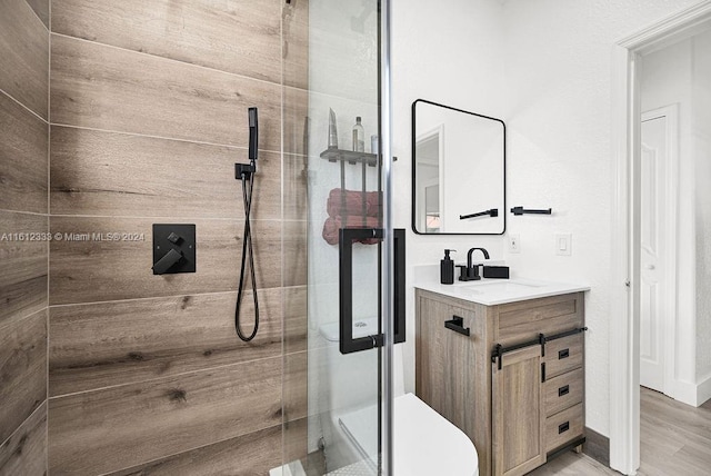 bathroom with hardwood / wood-style flooring, vanity, toilet, and walk in shower