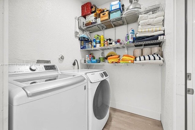 laundry area with washer and dryer and light hardwood / wood-style flooring