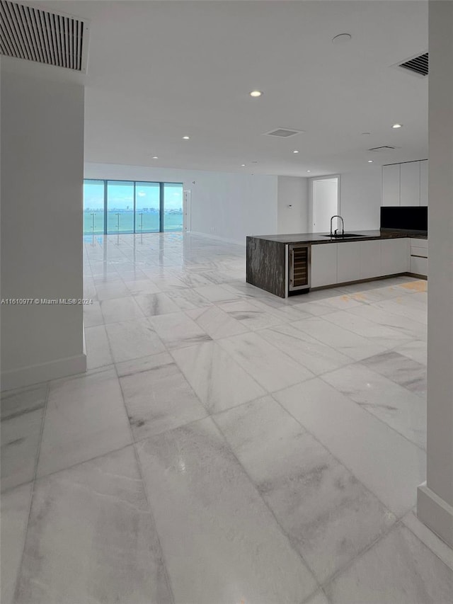 unfurnished living room with light tile floors, sink, and wine cooler