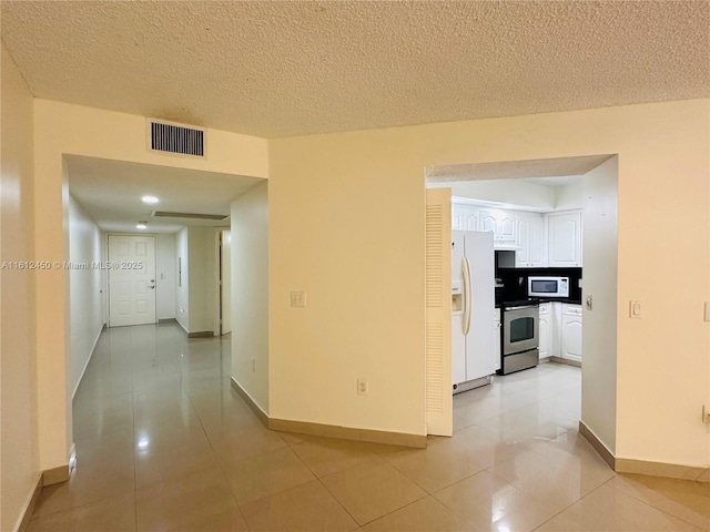 hall with a textured ceiling and light tile patterned flooring