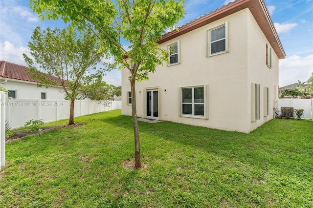 rear view of property featuring a lawn and central AC