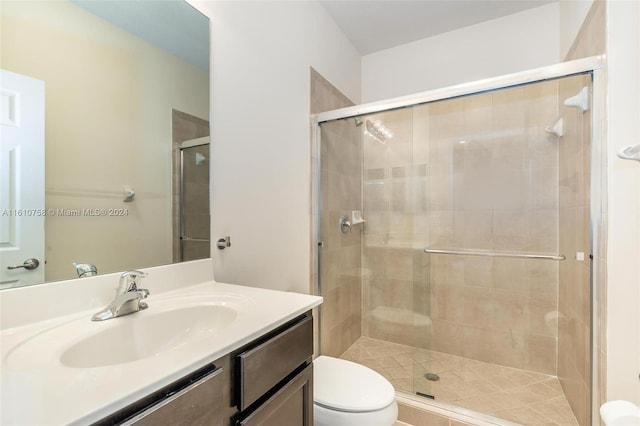 bathroom featuring vanity, toilet, and a shower with door