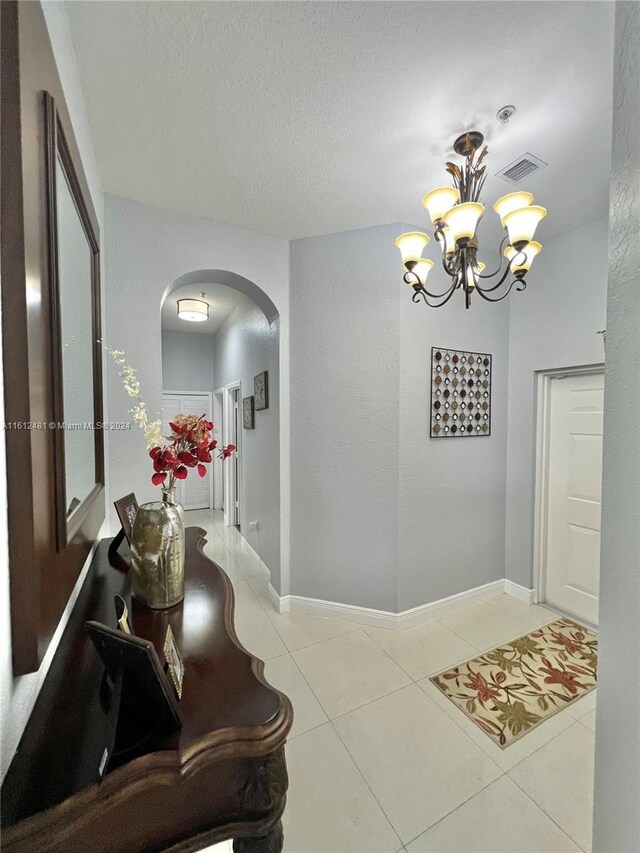 entrance foyer with tile flooring, an inviting chandelier, and a textured ceiling