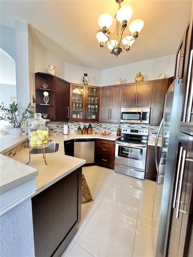 kitchen featuring an inviting chandelier, backsplash, light tile floors, hanging light fixtures, and appliances with stainless steel finishes