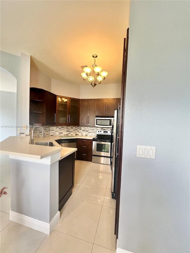 kitchen with dark brown cabinetry, tasteful backsplash, appliances with stainless steel finishes, sink, and light tile floors