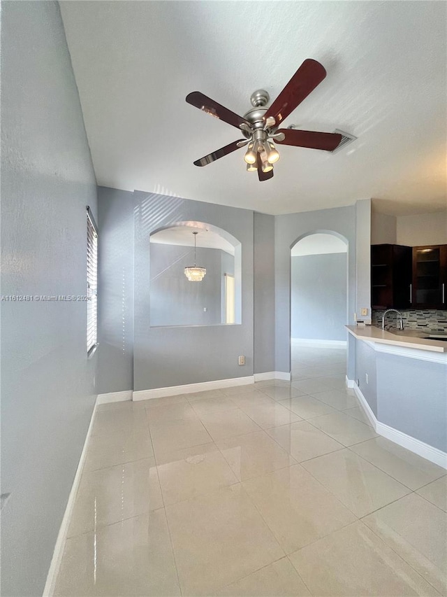 unfurnished living room featuring ceiling fan, sink, and light tile floors