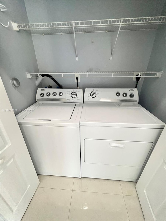 washroom with washer and dryer and light tile floors