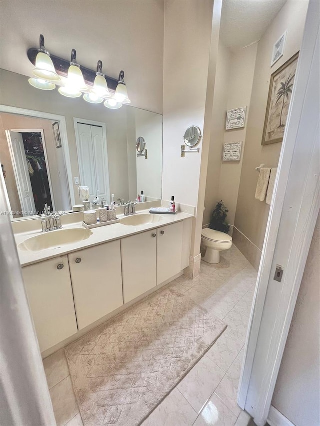 bathroom featuring double vanity, tile flooring, and toilet