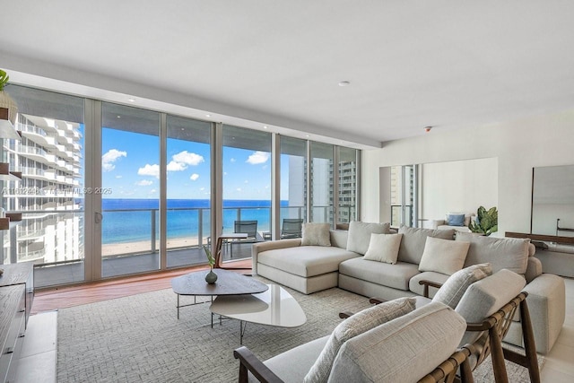 living room with floor to ceiling windows, a water view, and a healthy amount of sunlight