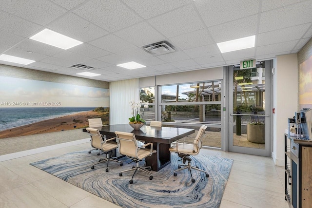 dining room featuring a drop ceiling, a water view, and light tile patterned floors