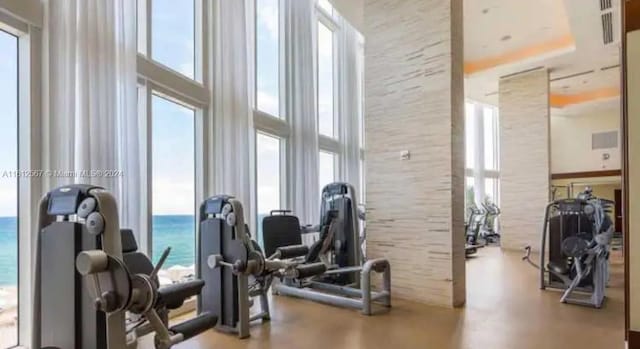 workout area featuring a high ceiling and a water view