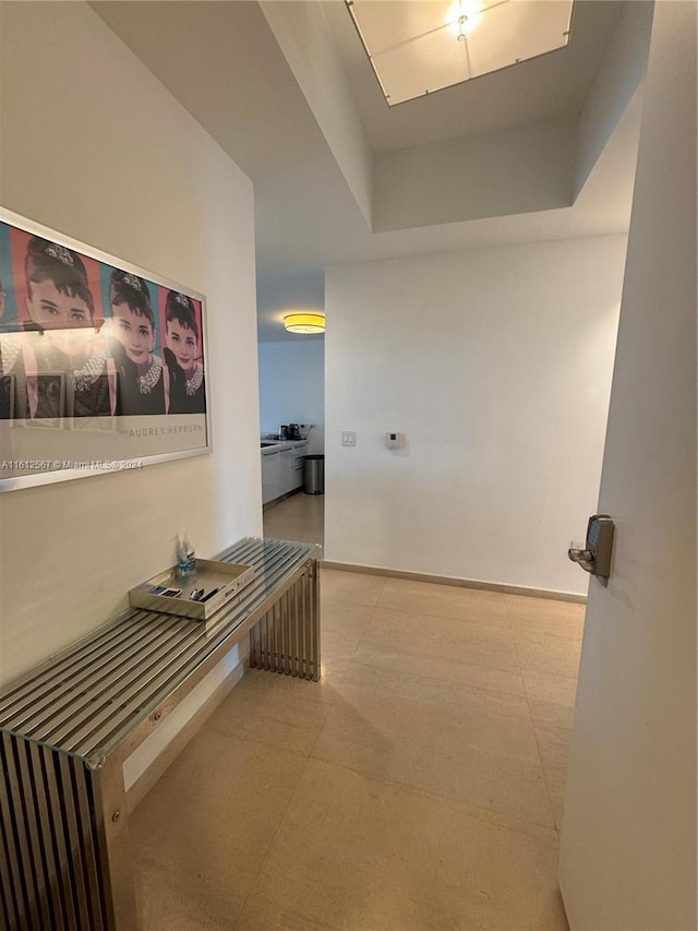 hallway featuring tile floors and a raised ceiling