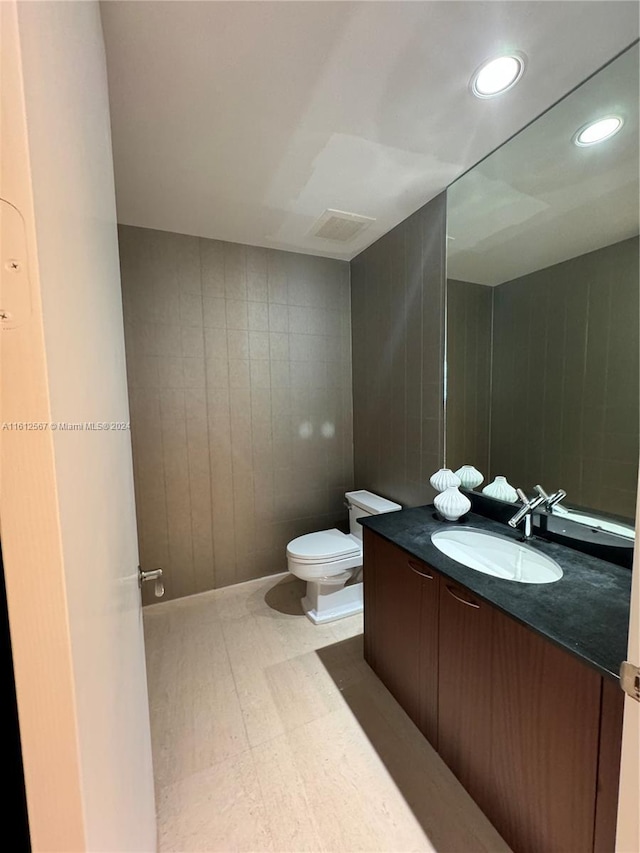 half bath with vanity, recessed lighting, visible vents, and toilet