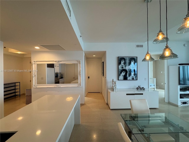 kitchen featuring white cabinetry, decorative light fixtures, and light tile flooring