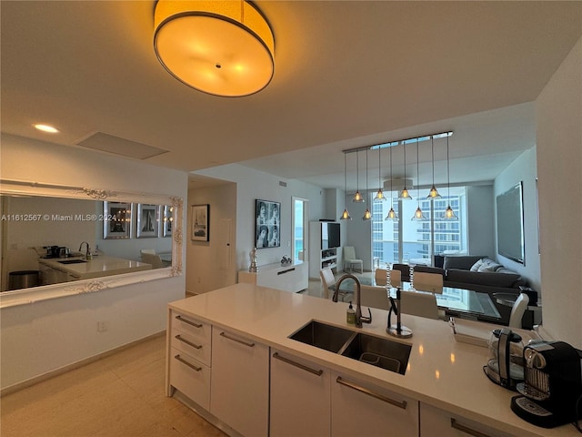 kitchen featuring sink, white cabinets, light tile floors, and hanging light fixtures