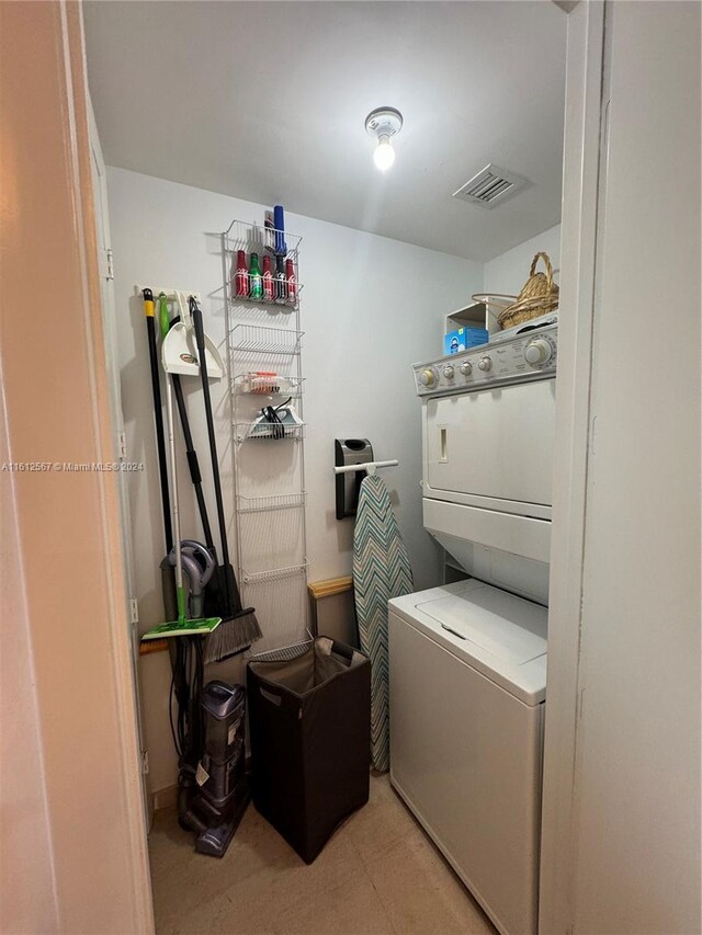 laundry room featuring laundry area, stacked washer / drying machine, visible vents, and light colored carpet