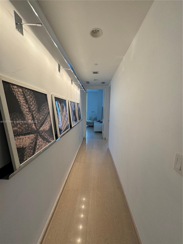 hallway featuring baseboards and visible vents