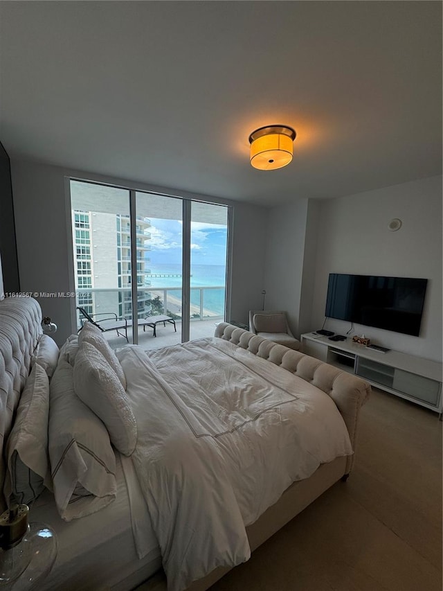 bedroom featuring hardwood / wood-style flooring, a water view, and access to exterior