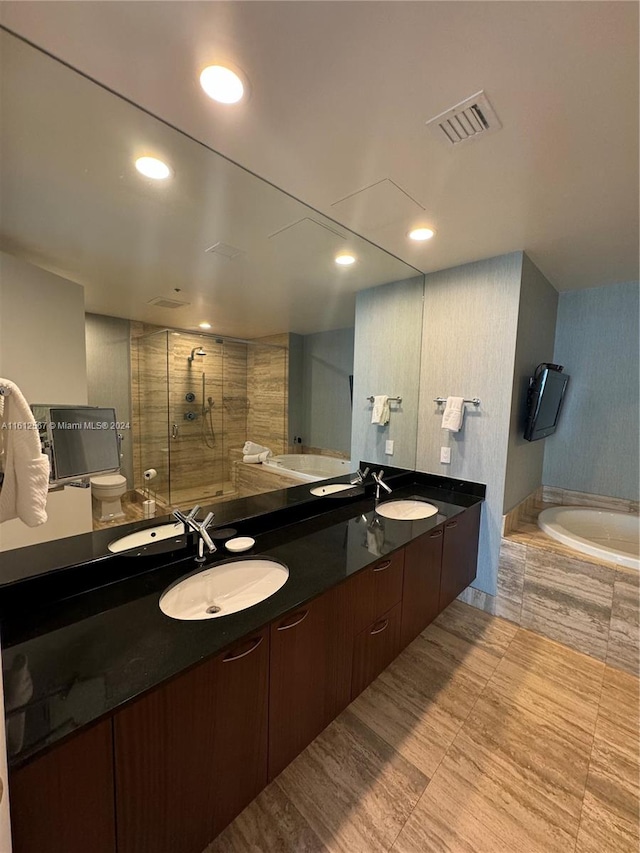 full bathroom featuring tile flooring, independent shower and bath, double sink, toilet, and large vanity