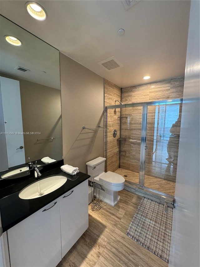 bathroom with walk in shower, vanity, and toilet