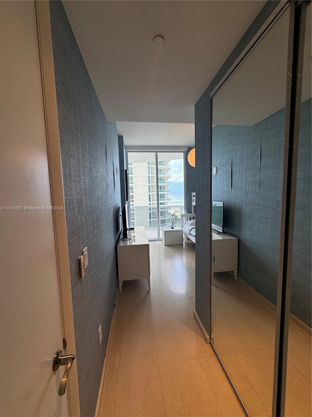 hall featuring light floors and wallpapered walls